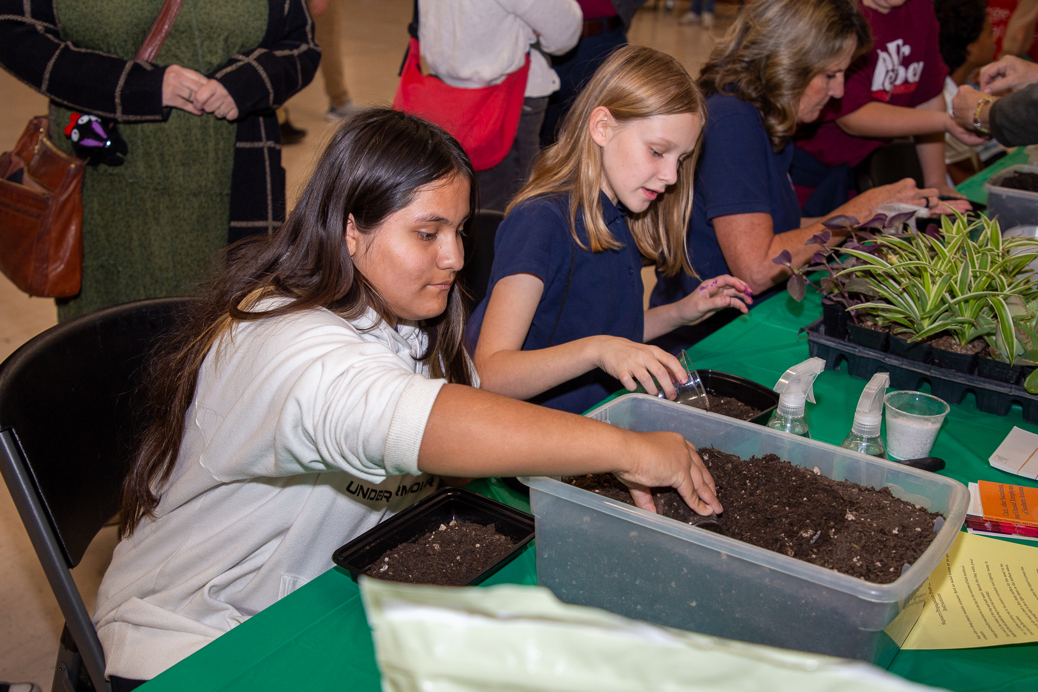 Two girls get their hands in the dirt in the garden section of the event