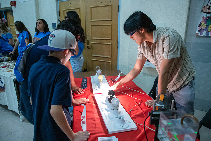 A man shows some kids an experiment with light bulbs