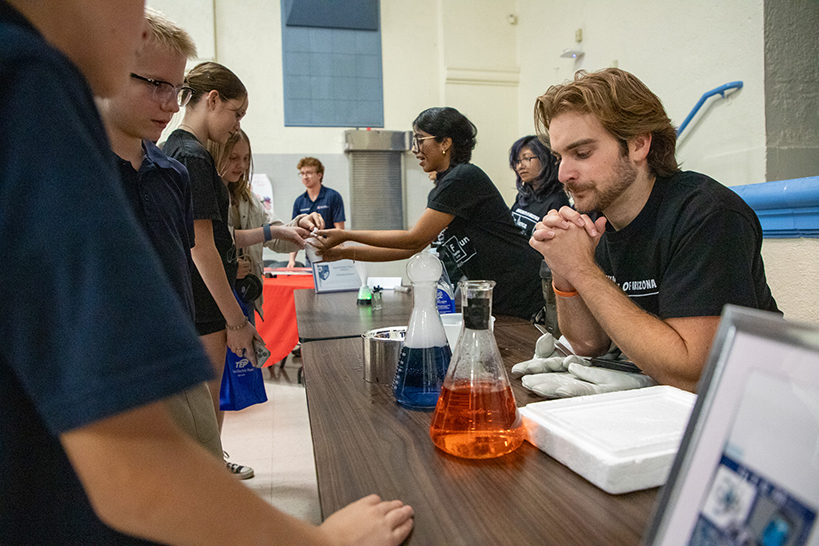 Two preteen boys look at some colorful chemicals in beakers