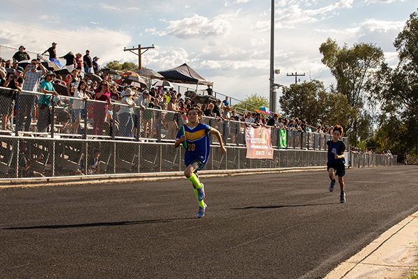 Two boys run down the track holding batons during the relay race