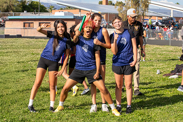 The track team poses for a silly group photo on the field