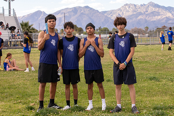 Four boys from the track team pose for a photo on the field