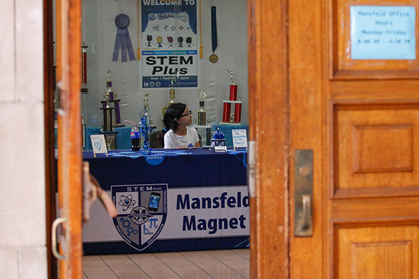 A girl sits at the welcome table for the STEM Night event