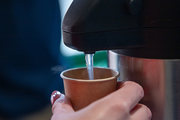 Closeup of a hand pouring hot water into a cup