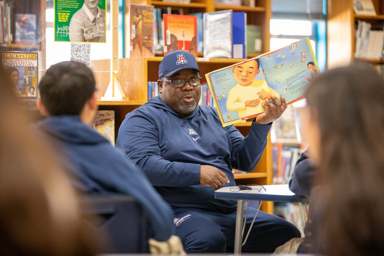 Alonso Carter holds up the book he's reading to students.